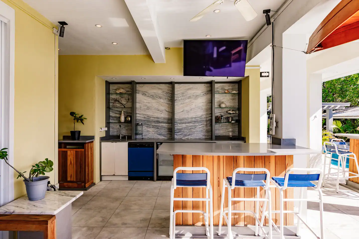 An outdoor kitchen with a grill, griddle, sink and dishwasher.